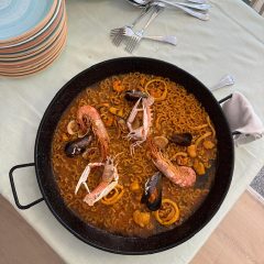 Fideuá marinera con mariscos servida en paellera sobre mesa preparada para compartir